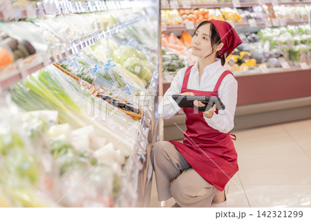 スーパーの野菜売り場でタブレットを使い商品管理をする女性店員 スーパーの野菜売り場でタブレットを使い商品管理をする女性店員 142321299