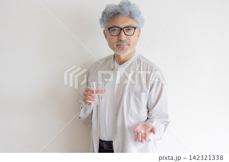 水と薬を手に健康管理をするシニア男性 142321338