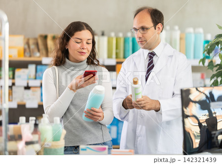 Woman buyer scans shampoo qr code with man pharmacist Woman buyer scans shampoo qr code with man pharmacist 142321439
