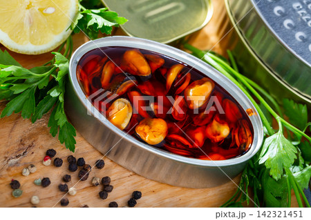 Pickled mussels in open tin can on background with lemon and greens 142321451