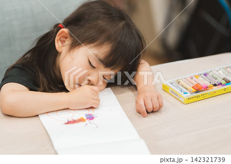 自宅で塗り絵をしながら寝てしまった3歳の女の子 自宅で塗り絵をしながら寝てしまった3歳の女の子 142321739
