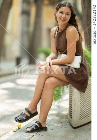 Young woman sitting on a concrete flower bed Young woman sitting on a concrete flower bed 142322142