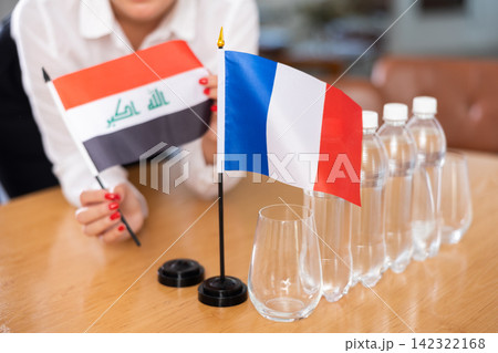 Flags of Iraq and France stand on negotiating table in office 142322168