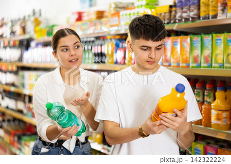 Young couple of customers diligently picking out soft drinks Young couple of customers diligently picking out soft drinks 142322224