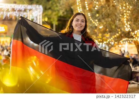 Happy girl with German flag in city Christmas fair 142322317