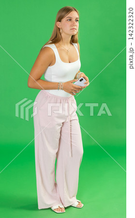 Teenage girl looking around in front of green screen 142322320