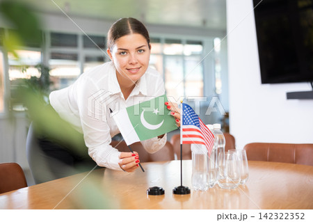Young woman putting flags of Pakistan and USA on table in office 142322352