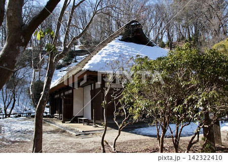 早春の薬師池公園（古民家）｜雪化粧の茅葺き屋根を春日が優しく照らす、静かなひととき 142322410