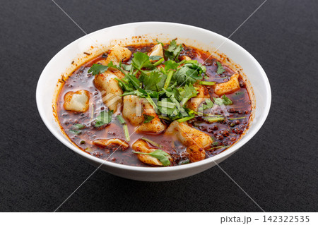 spicy dumpling soup with chili oil and coriander served in a bowl on black background spicy dumpling soup with chili oil and coriander served in a bowl on black background 142322535