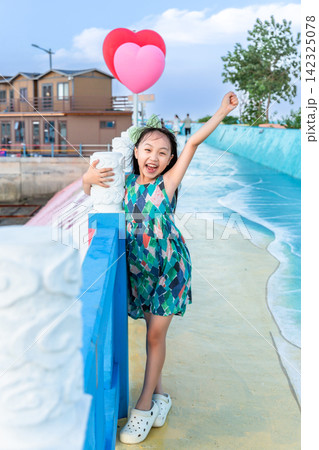 Cute little girl posing playfully on a colorful pedestrian walkway next to the ocean. Cute little girl posing playfully on a colorful pedestrian walkway next to the ocean. 142325078