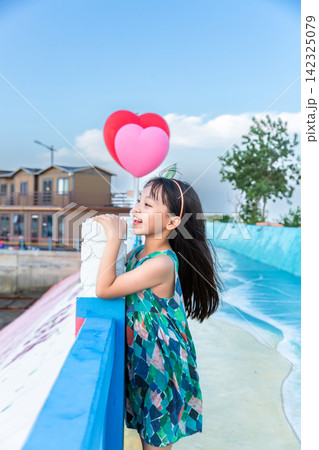 Cute little girl posing playfully on a colorful pedestrian walkway next to the ocean. Cute little girl posing playfully on a colorful pedestrian walkway next to the ocean. 142325079