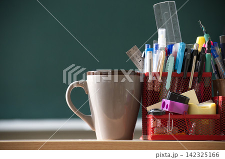 Stationery Holder with Assorted Pens and Rulers Next to Coffee Mug on Desk in Classroom Stationery Holder with Assorted Pens and Rulers Next to Coffee Mug on Desk in Classroom 142325166