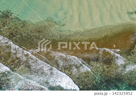 Aerial downward view of ocean waves crashing over the rugged rocky coastline at Brooms Head, capturing white surf, exposed rock formations and surrounding Pacific Ocean along the Clarence Valley coast Aerial downward view of ocean waves crashing over the rugged rocky coastline at Brooms Head, capturing white surf, exposed rock formations and surrounding Pacific Ocean along the Clarence Valley coast 142325952