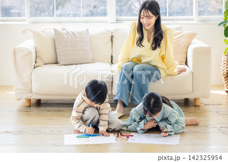 リビングでお絵かきをする子供たちを見守る母親 リビングでお絵かきをする子供たちを見守る母親 142325954