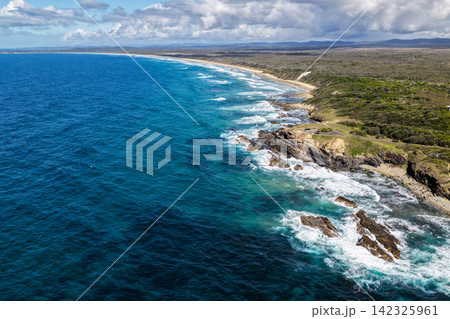 Aerial view of the Brooms Head headland surrounded by the Pacific Ocean, with the long sandy shoreline of Sand Dune Beach stretching along the coast and surrounding natural landscape in the Clarence Aerial view of the Brooms Head headland surrounded by the Pacific Ocean, with the long sandy shoreline of Sand Dune Beach stretching along the coast and surrounding natural landscape in the Clarence 142325961