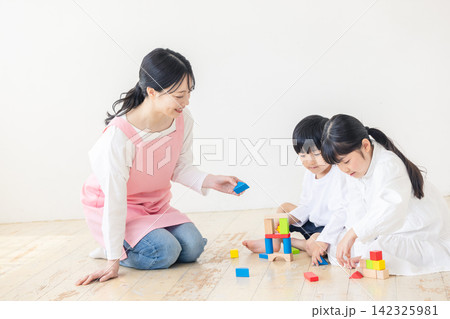 子供たちと一緒に積み木で遊ぶ笑顔の保育士 子供たちと一緒に積み木で遊ぶ笑顔の保育士 142325981