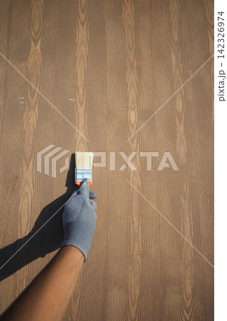 Hand holding paintbrush on wooden surface Hand holding paintbrush on wooden surface 142326974