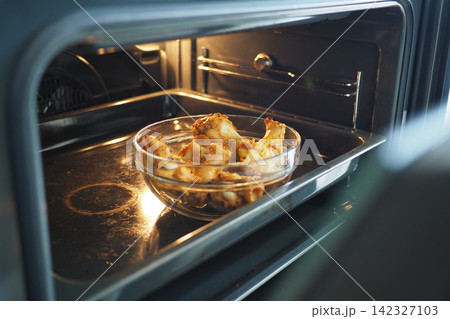 Cooked chicken wings placed inside an oven Cooked chicken wings placed inside an oven 142327103
