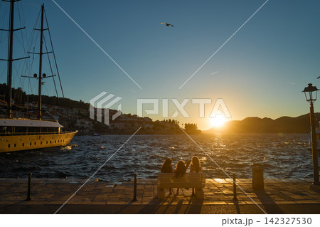 クロアチア コルチュラの港で夕日を眺める女性たちと帆船 クロアチア コルチュラの港で夕日を眺める女性たちと帆船 142327530