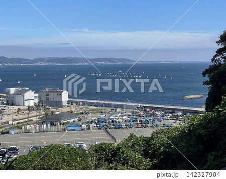 晴天の江の島ヨットハーバーと相模湾に浮かぶセーリングボート 晴天の江の島ヨットハーバーと相模湾に浮かぶセーリングボート 142327904