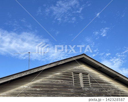 Old Wooden Roof Gable With Antenna Under Blue Cloudy Sky 142328587