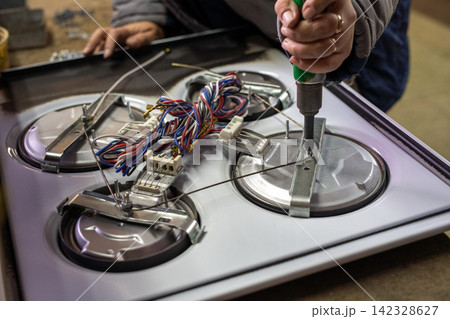 Hand using screwdriver on appliance wiring during repair 142328627