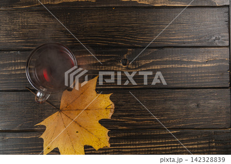 Cozy mug of tea next to autumn leaves on a wooden table Cozy mug of tea next to autumn leaves on a wooden table 142328839