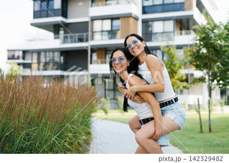 Happy Woman Riding on Her Sisters Back Outdoors Happy Woman Riding on Her Sisters Back Outdoors 142329482
