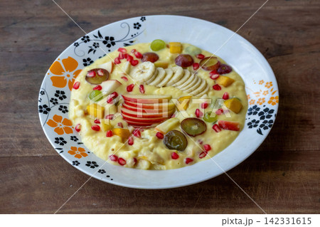 Delicious creamy fruit custard served in decorated plate on wooden table surface. Sweet homemade dessert, summer refreshment, and healthy eating concept. 142331615