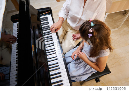 Woman piano teacher giving a piano lesson to a young girl at home 142331906