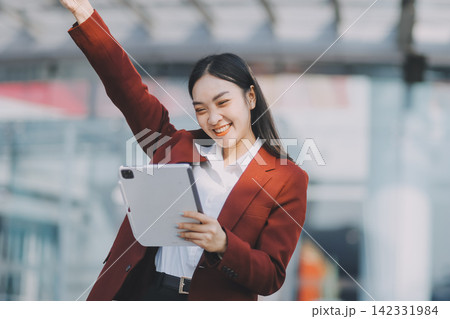 Young professional woman talking on phone and holding coffee outside modern office building Young professional woman talking on phone and holding coffee outside modern office building 142331984