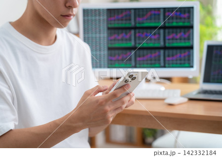 家で株式投資をする若い男性 家で株式投資をする若い男性 142332184