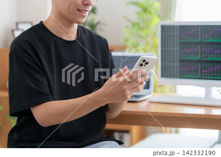 家で株式投資をする若い男性 家で株式投資をする若い男性 142332190