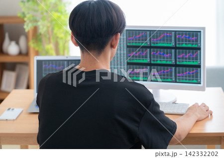 家で株式投資をする若い男性 142332202