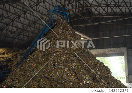 Massive plastic waste pile under a conveyor belt at a recycling plant, waste sorting, recycling, sustainability, circular economy, and environmental protection. Massive plastic waste pile under a conveyor belt at a recycling plant, waste sorting, recycling, sustainability, circular economy, and environmental protection. 142332371