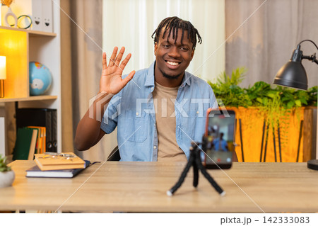 African American young man on home table records online lesson on phone and speaks with confidence 142333083