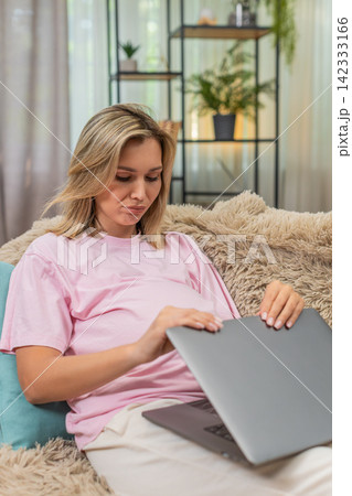 Pregnant woman closes laptop after client rejection in freelance work showing disappointed posture Pregnant woman closes laptop after client rejection in freelance work showing disappointed posture 142333166