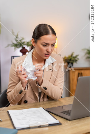 Young businesswoman hits workspace in anger crumples report exhales calms and returns to editing Young businesswoman hits workspace in anger crumples report exhales calms and returns to editing 142333194