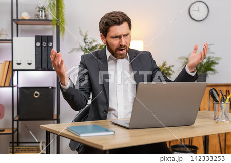 Middle-aged businessman sees laptop freeze eyes widen press key reboots system upset data loss after 142333253