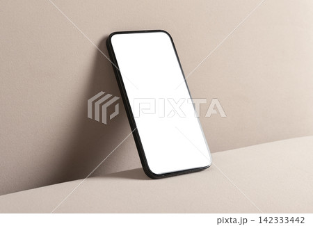 Smartphone with blank screen on beige surface. Minimal mobile mockup with copy space and clean studio lighting. Ideal for app advertising and branding.. Smartphone with blank screen on beige surface. Minimal mobile mockup with copy space and clean studio lighting. Ideal for app advertising and branding.. 142333442