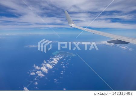 日本　沖縄上空を飛ぶ旅客機の窓から見た与論島と青空と海 142333498