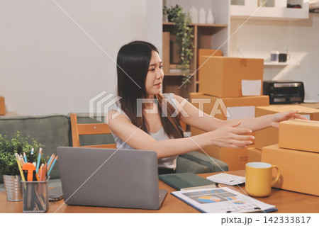 Startup SME small business entrepreneur of freelance Asian woman wearing apron using laptop and box to receive and review orders online to prepare to pack sell to customers, online sme business ideas. Startup SME small business entrepreneur of freelance Asian woman wearing apron using laptop and box to receive and review orders online to prepare to pack sell to customers, online sme business ideas. 142333817
