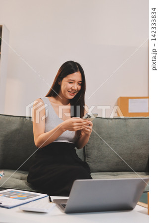 Startup SME small business entrepreneur of freelance Asian woman wearing apron using laptop and box to receive and review orders online to prepare to pack sell to customers, online sme business ideas. Startup SME small business entrepreneur of freelance Asian woman wearing apron using laptop and box to receive and review orders online to prepare to pack sell to customers, online sme business ideas. 142333834