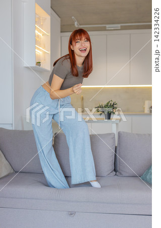 Young woman dances and jumps to loud music playful party mood carefree joy weekend vacation freedom 142334226