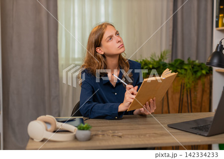 Young woman on home table reading study book marking key line while continuing calm learning process 142334233