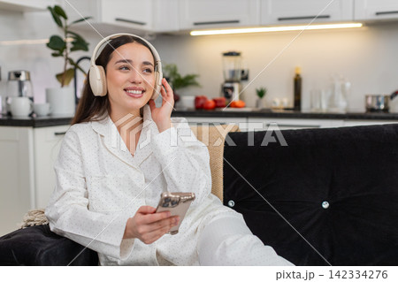 Young woman in wireless headphones listens to music with smartphone relax closed eyes chill zen mood 142334276