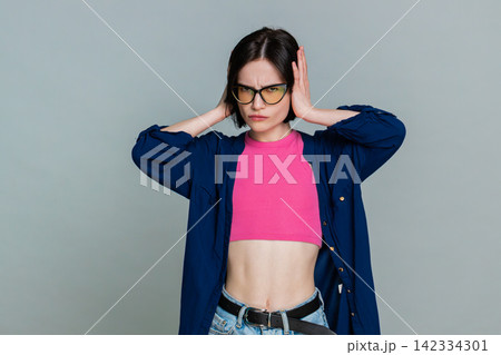 Woman covering ears with hands turning head away indicating unwillingness to hear refuse gesture Woman covering ears with hands turning head away indicating unwillingness to hear refuse gesture 142334301