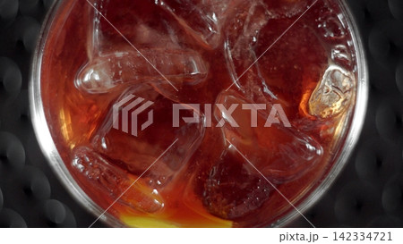 Cold refreshing dark beverage with ice cubes and lemon slice in a glass, top view, bubbles creating a refreshing texture Cold refreshing dark beverage with ice cubes and lemon slice in a glass, top view, bubbles creating a refreshing texture 142334721