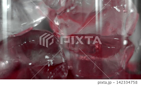 Ice cubes melting in red beverage, cold refreshing drink close-up, liquid texture and abstract patterns 142334758