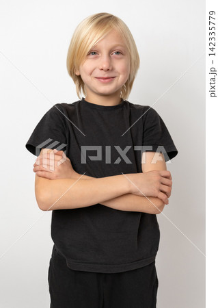Blond boy with a cheerful facial expression standing against a white backdrop, portraying happiness, confidence, and innocence 142335779